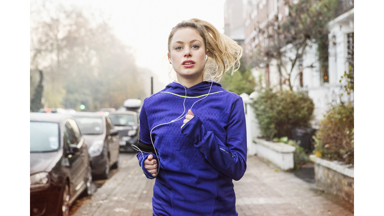 Female runner running down urban street.