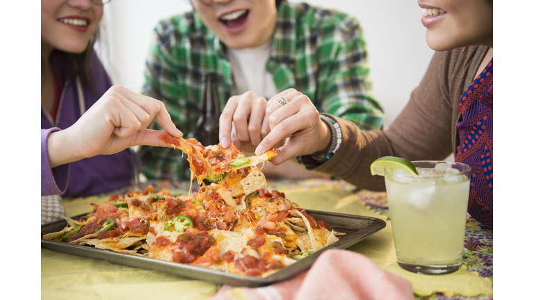Young women and man eating nachos with melted cheese