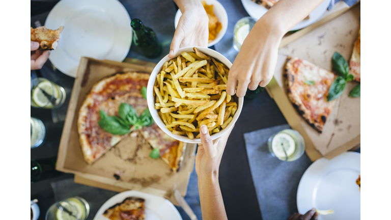 Hand taking French fries from bowl