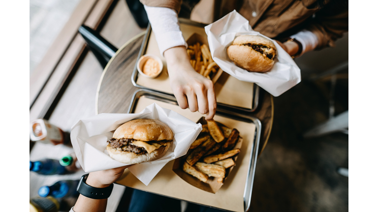 Overhead view of couple sitting by the window eating burgers with french fries in a restaurant