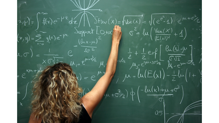 student solves mathematics problem on blackboard