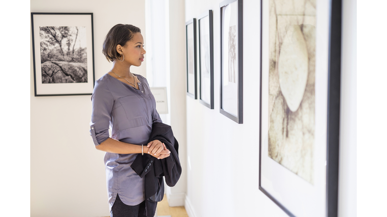 Black woman admiring paintings in art gallery