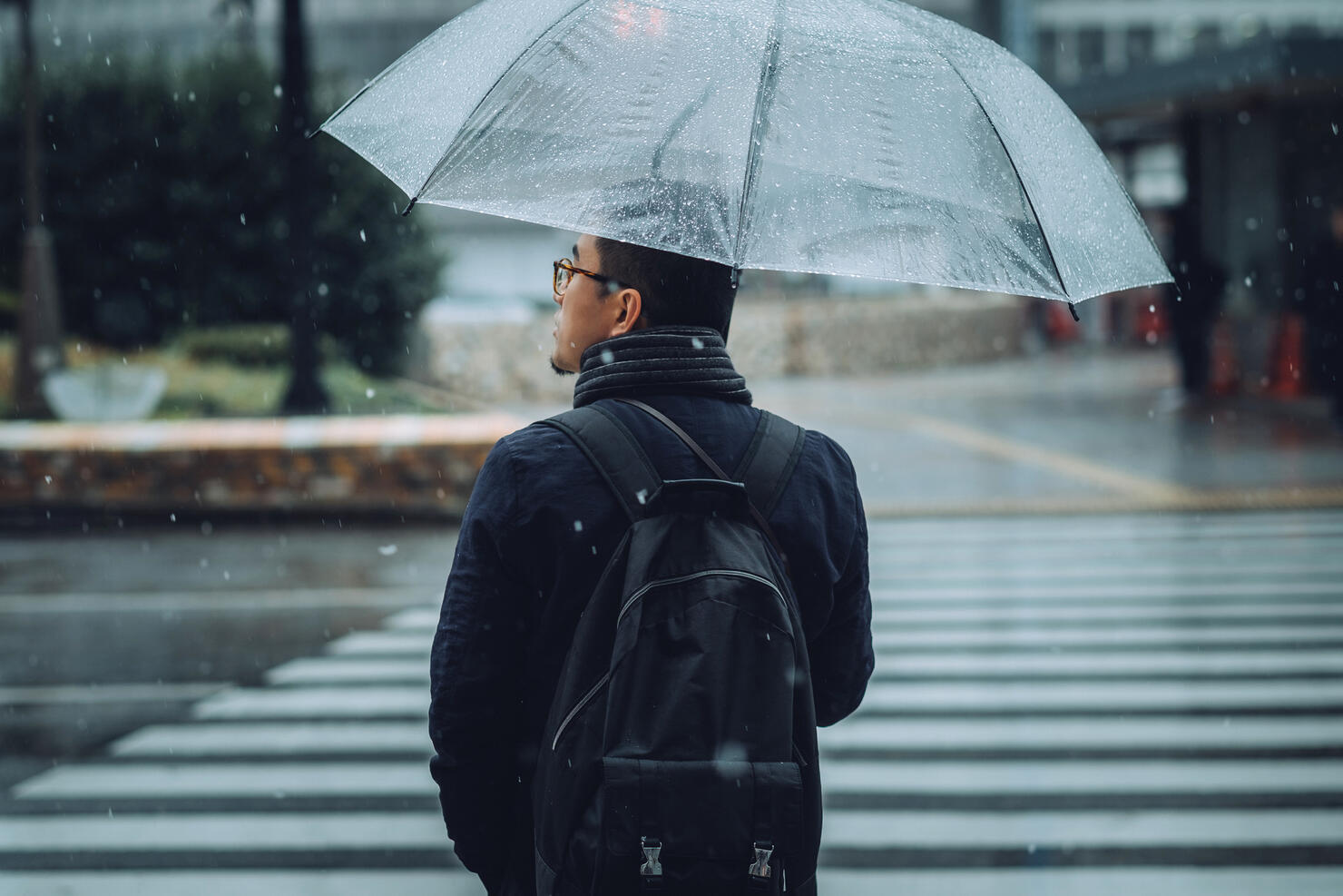 Rear view of man with umbrella walking in city in snow during Winter