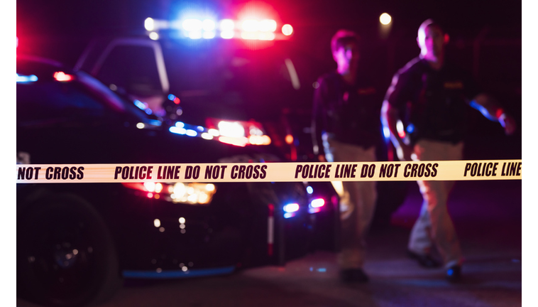 Two police officers behind crime scene tape