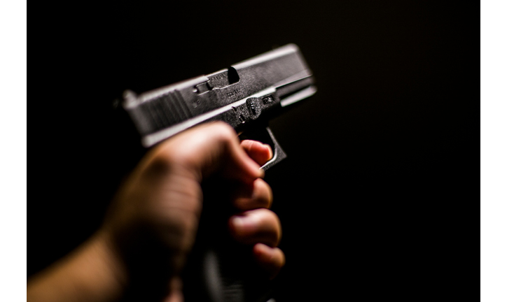 Cropped Hand Holding Gun Against Black Background