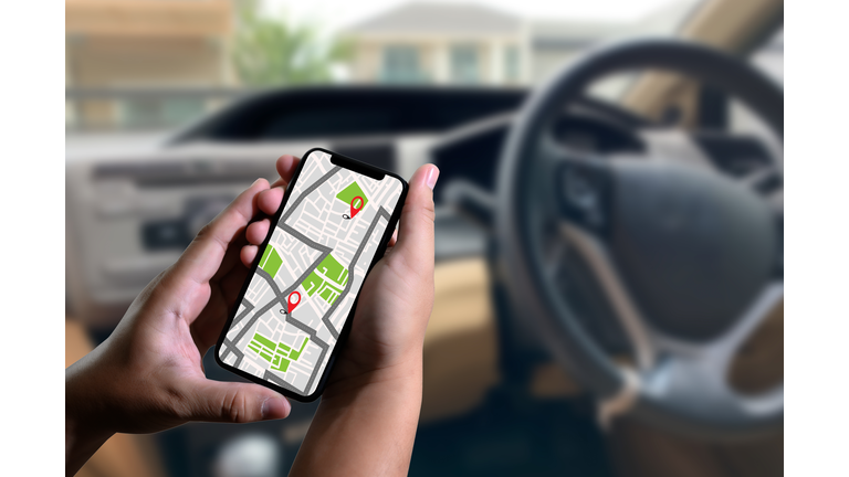 Cropped Hands Using Map In Mobile Phone During Road Trip