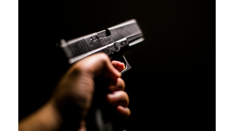 Cropped Hand Holding Gun Against Black Background
