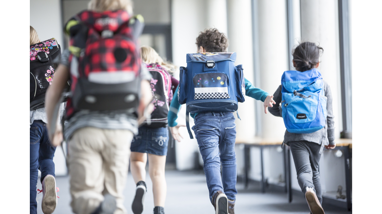 Rear view of pupils rushing down school corridor