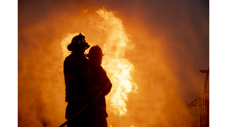 Silhouette of two firefighter in front of the big fire, Fire insurance concept