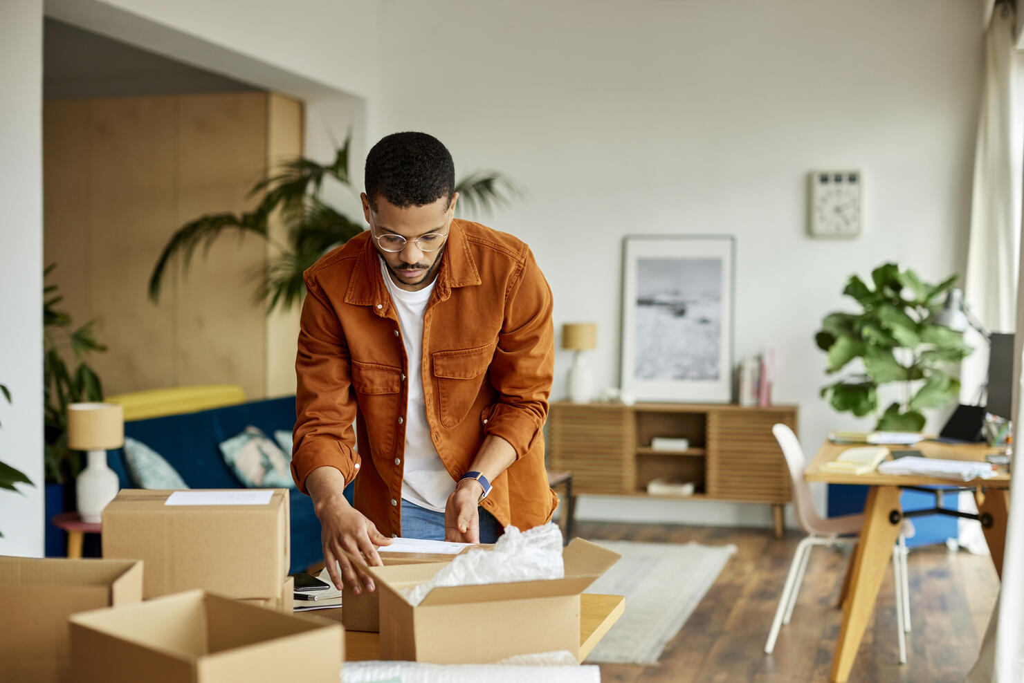 Young Businessman Packing Cardboard Box At Table