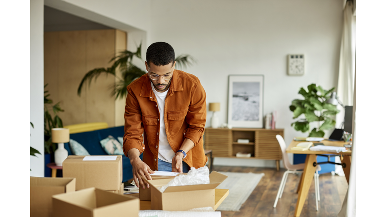 Young Businessman Packing Cardboard Box At Table