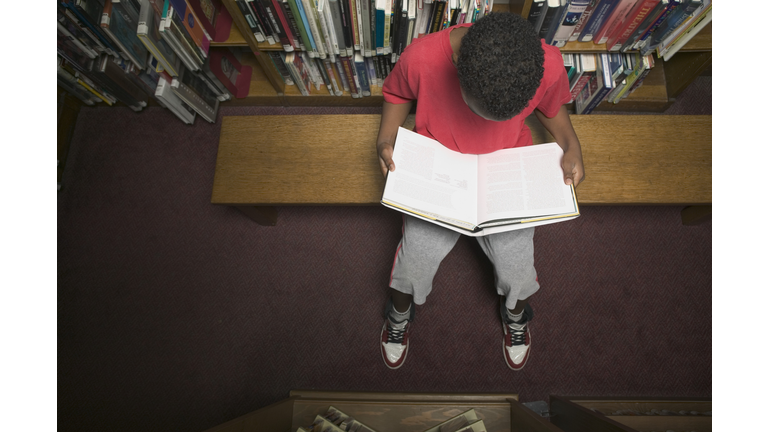 High angle view of a young boy reading a book in a library