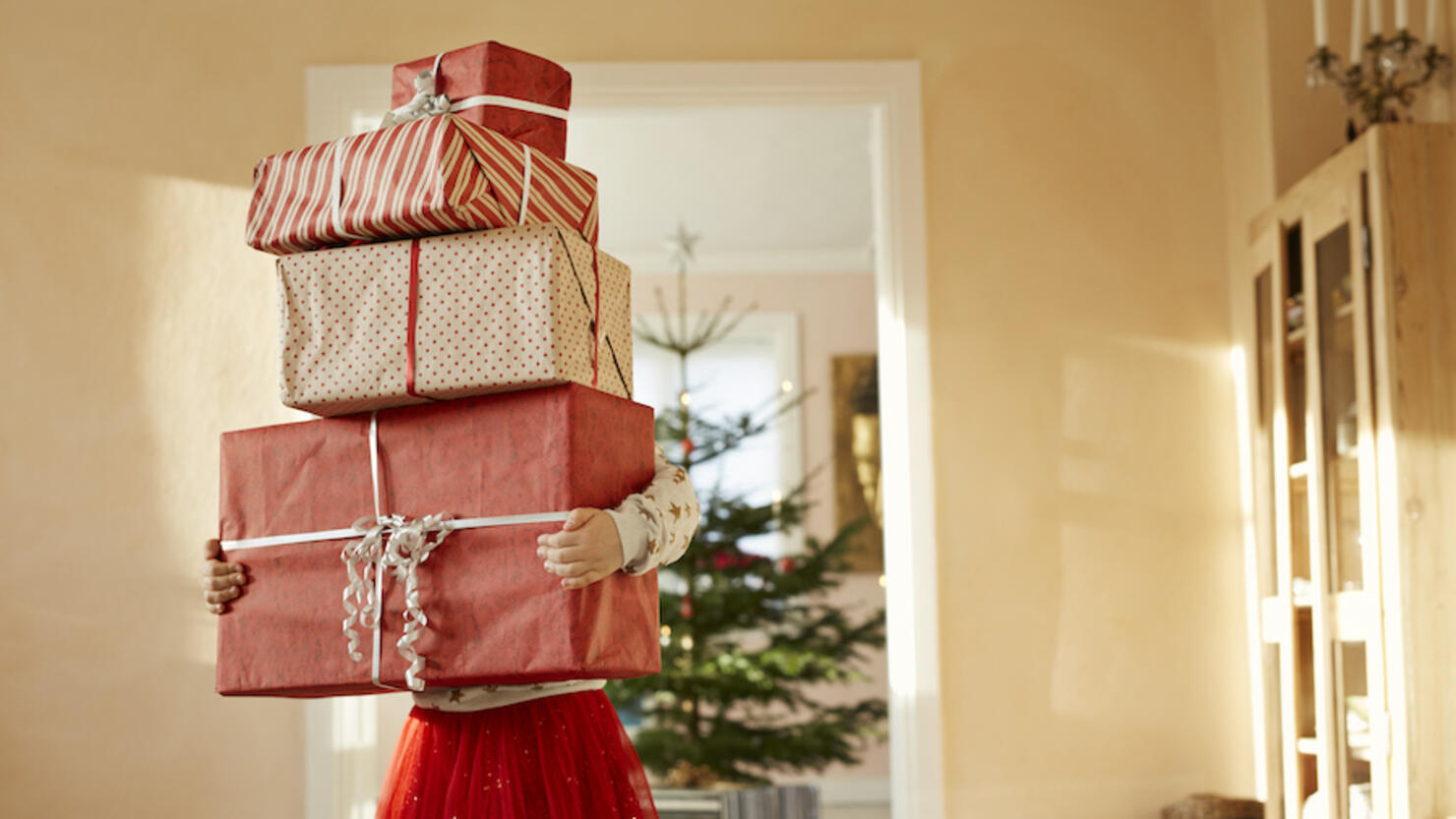 Girl holding tall stack of christmas presents