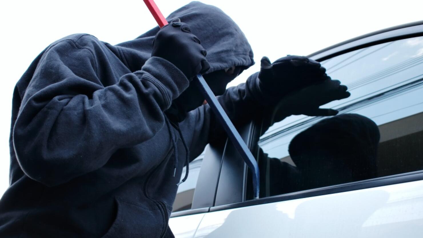 Masked burglar trying to get into a car