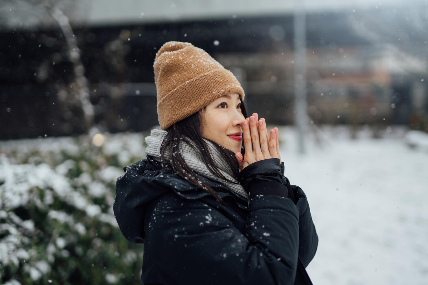 Beautiful Young Asian Woman Warming Her Hands In The Snow