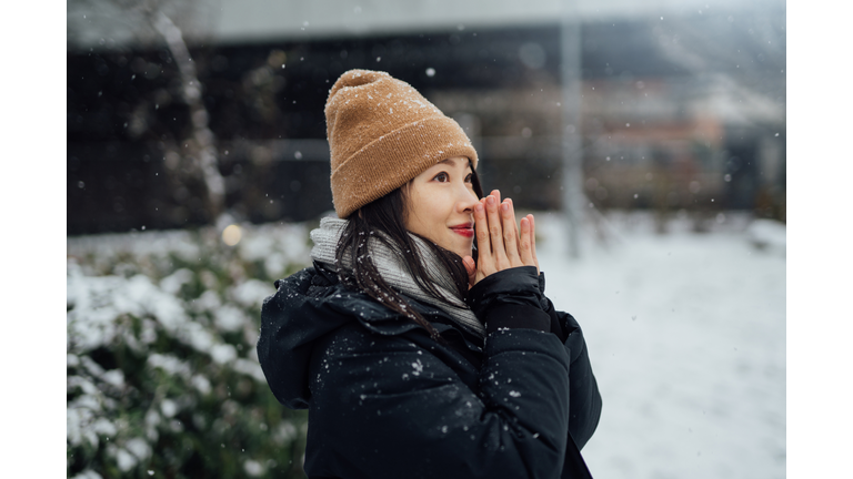 Beautiful Young Asian Woman Warming Her Hands In The Snow