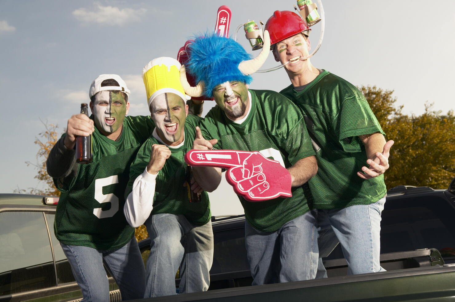 Four male football fans wearing face paint, gesticulating