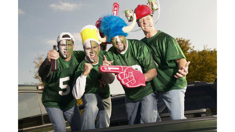 Four male football fans wearing face paint, gesticulating