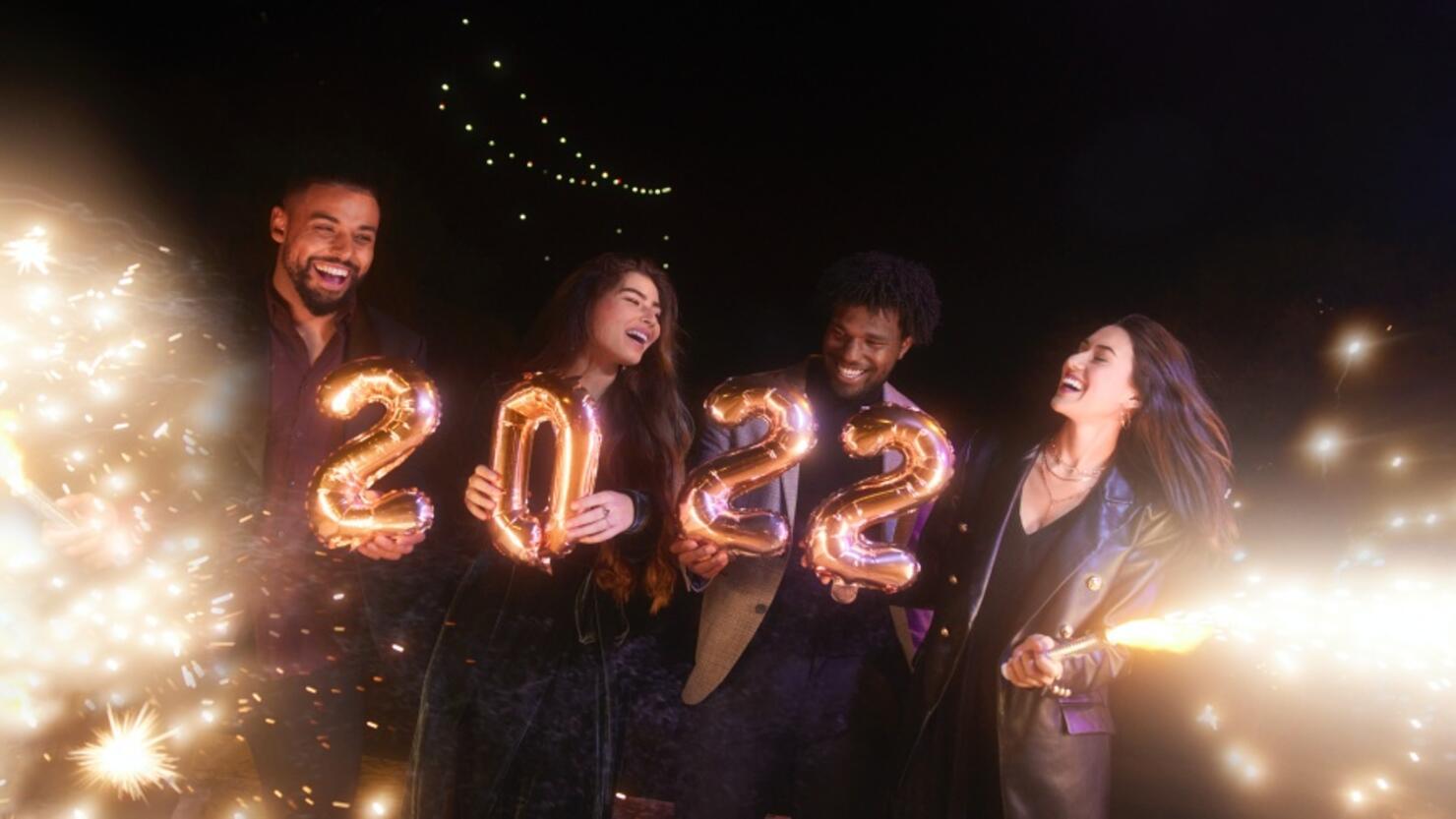 Group of friends celebrating new years holding 2022 balloons and sparklers