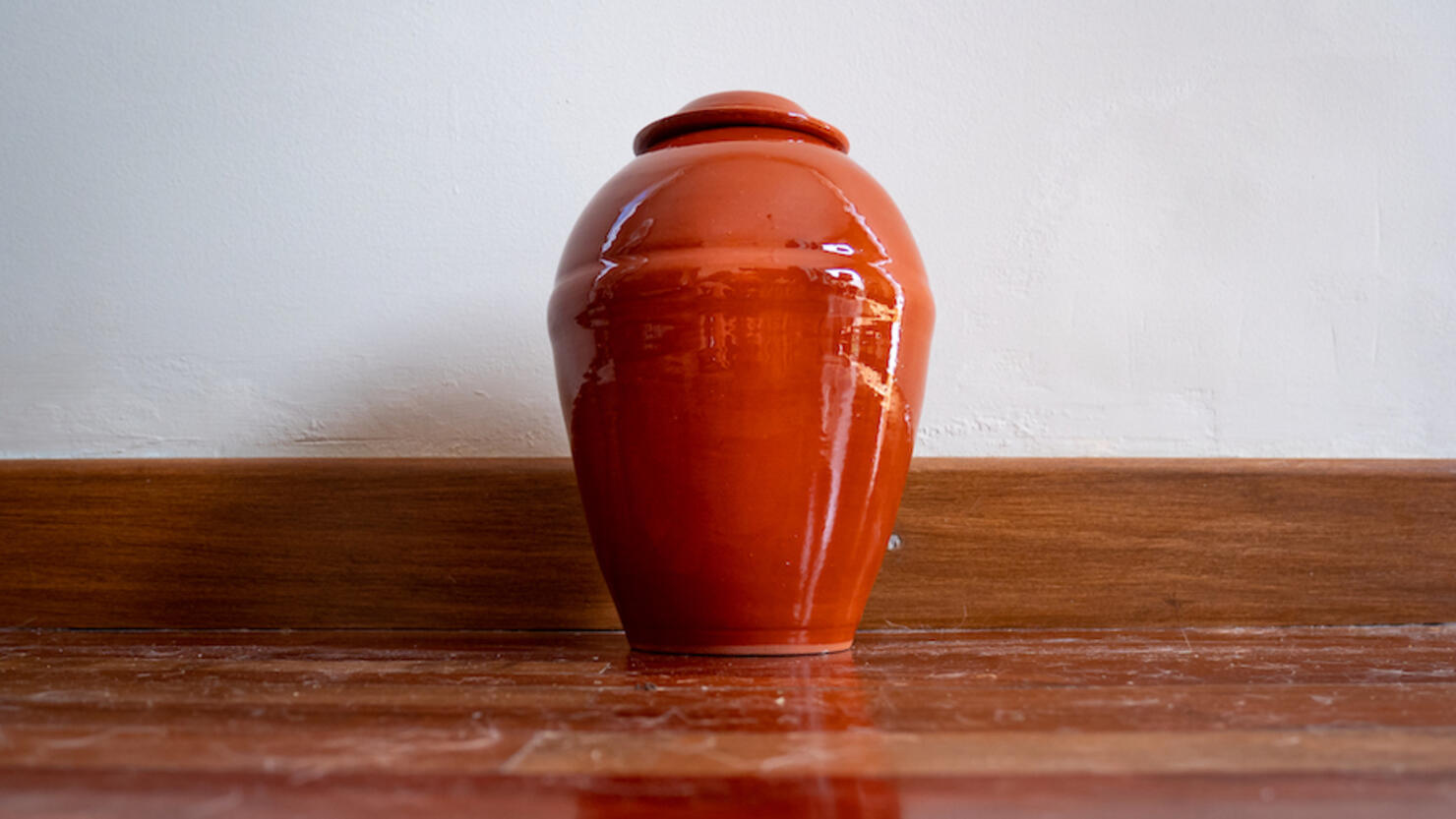Orange Urn Leaning Against the White Wall