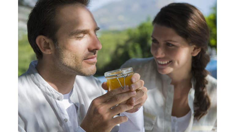 Man smelling marmalade with a woman smiling beside him