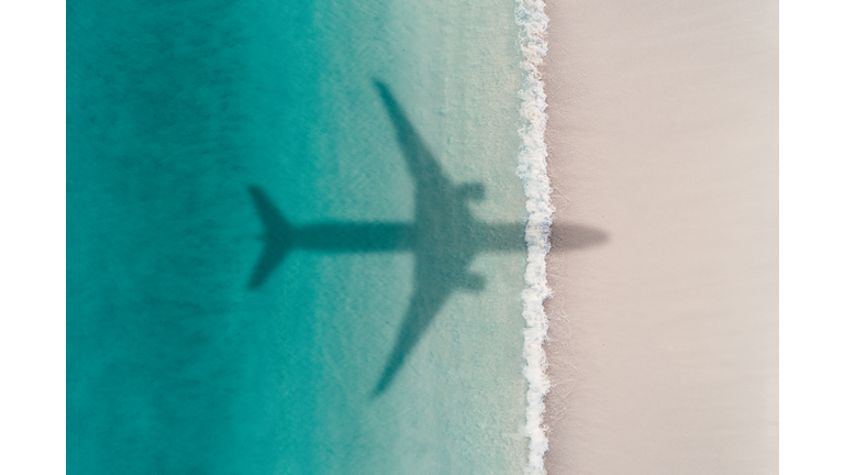 Aerial shot showing an aircraft shadow flying over an idyllic beach scene, Barbados