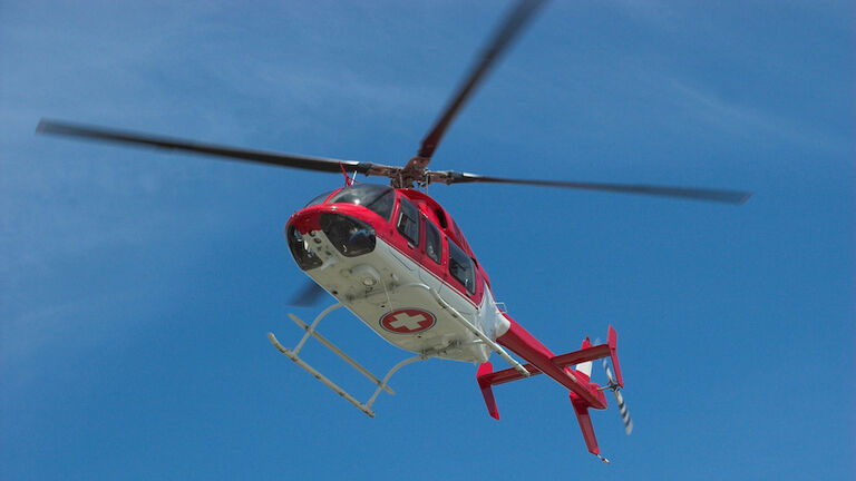 Closeup of flying red helicopter in contrast with blue sky