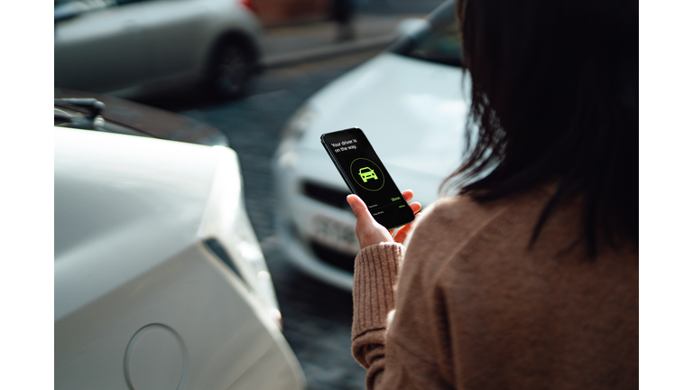 Young Woman Ordering Taxi Using Mobile App On Smartphone