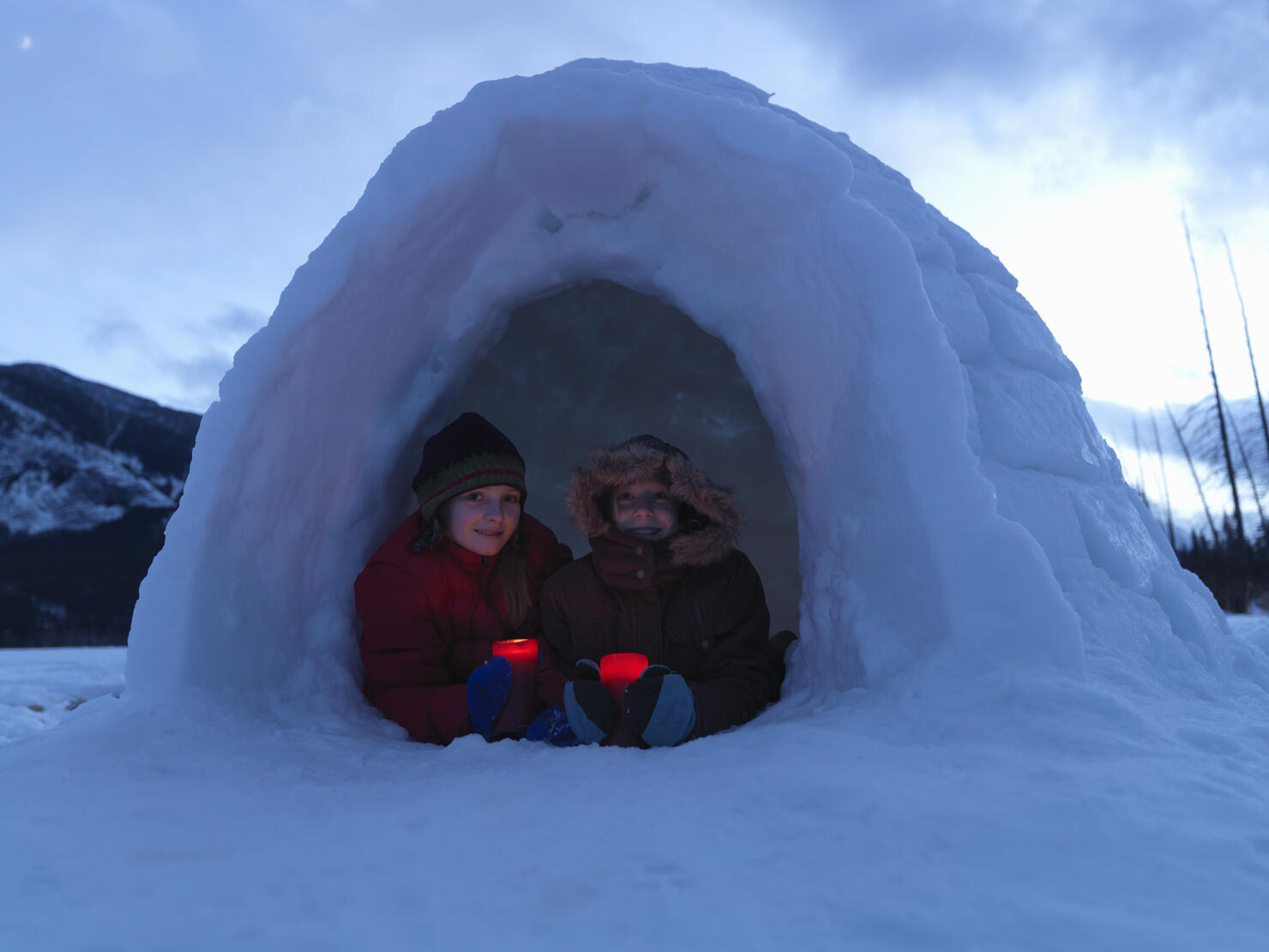 Girls (8-13) holding candles in igloo, smiling, portrait