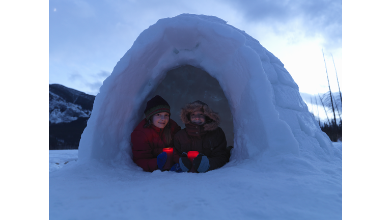 Girls (8-13) holding candles in igloo, smiling, portrait