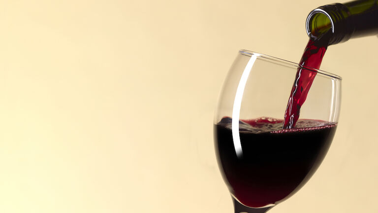 Pouring glass of red wine with copy space