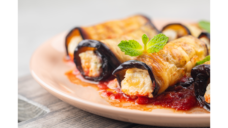 Close-up of eggplant rolls with ricotta, parmesan cheese and tomato sauce. Light background.