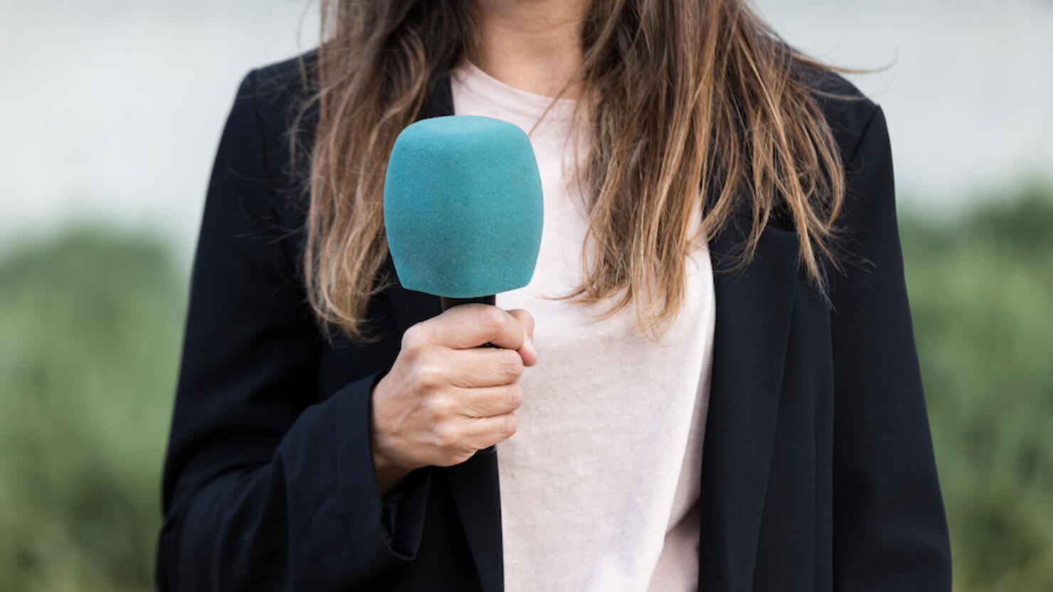 Close-up of journalist woman holding a microphone - stock photo