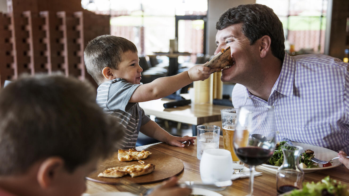 Boy feeding pizza to father in restaurant