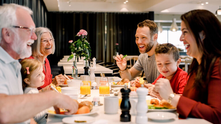 Cheerful family talking while having food at table in restaurant