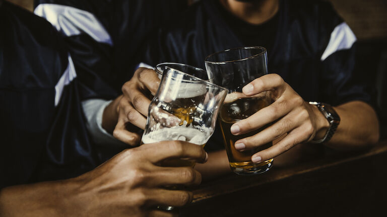 Male football fans toasting beer glasses in bar