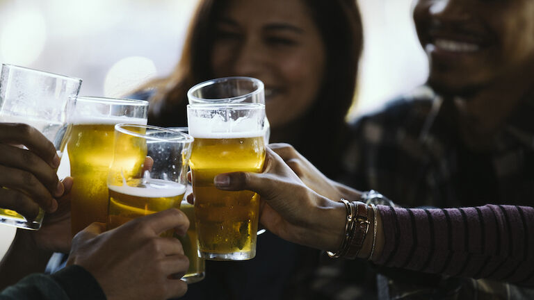 Close-up of happy friends toasting beer glasses in pub