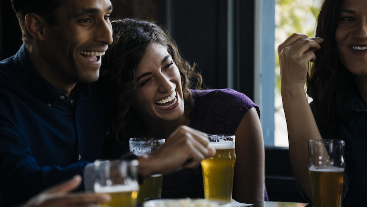 Friends laughing over drinks in bar