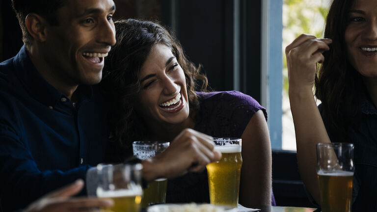 Friends laughing over drinks in bar