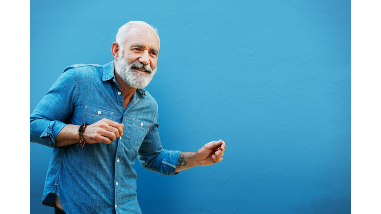 Man dancing next to blue wall