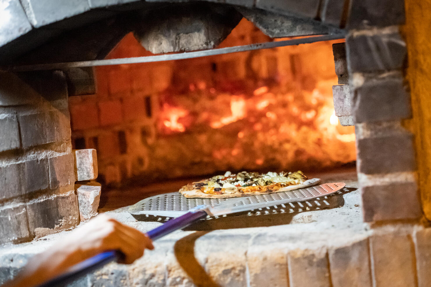 Cook baking pizza in a wood fire Brick oven