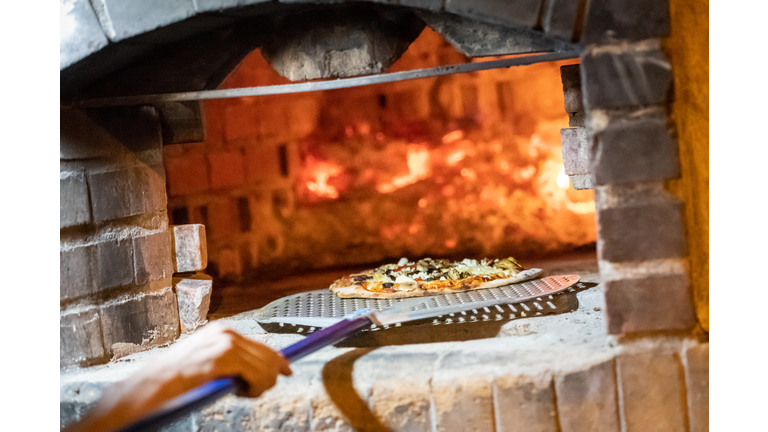Cook baking pizza in a wood fire Brick oven