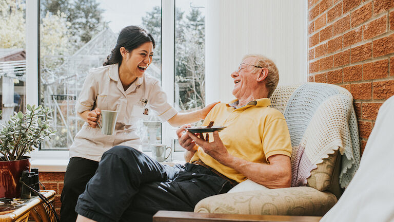 Female care assistant spends some time with an Elderly man in his home