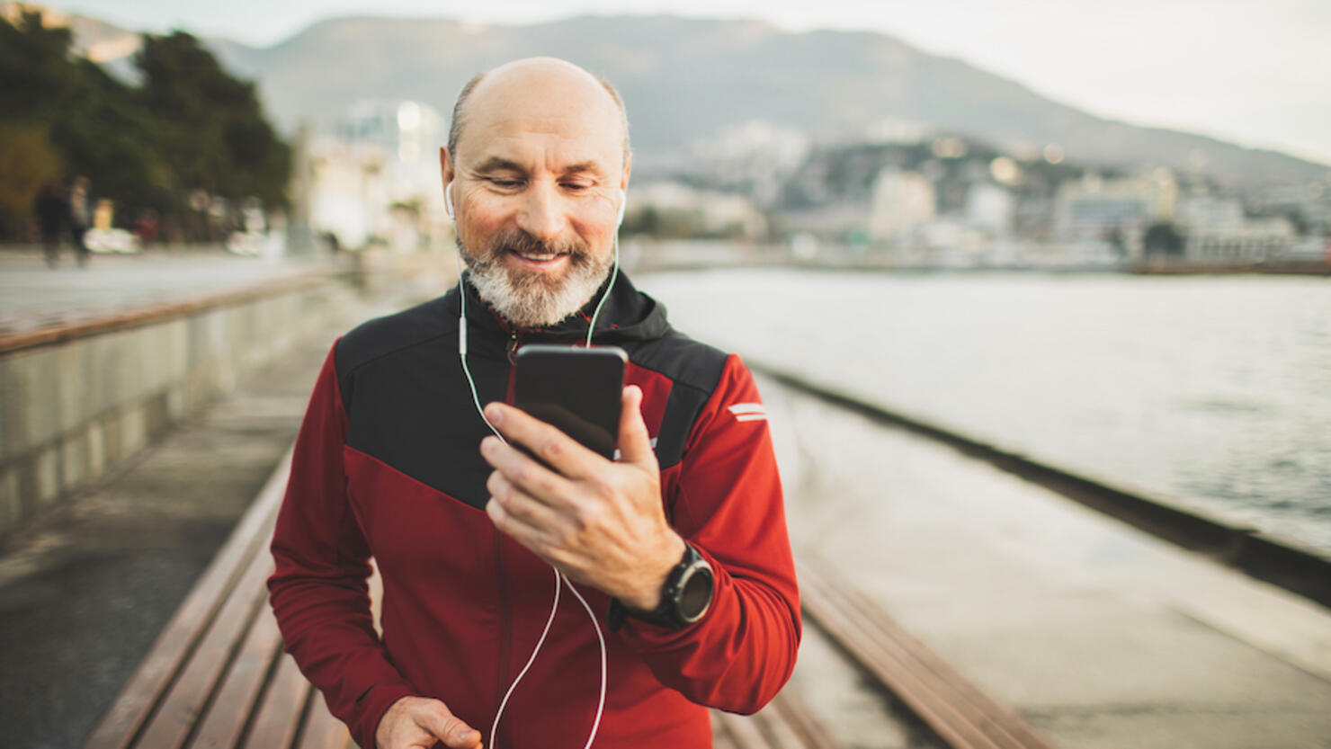 Senior adult athlete share training results online with friends by video communicating on phone