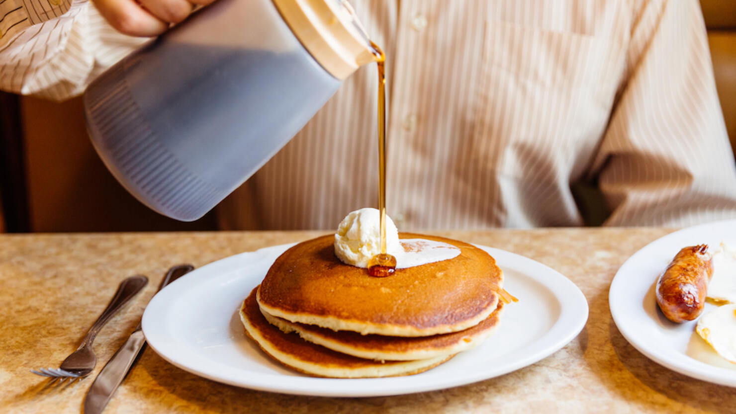 Man pouring maple syrup over pancakes in the diner