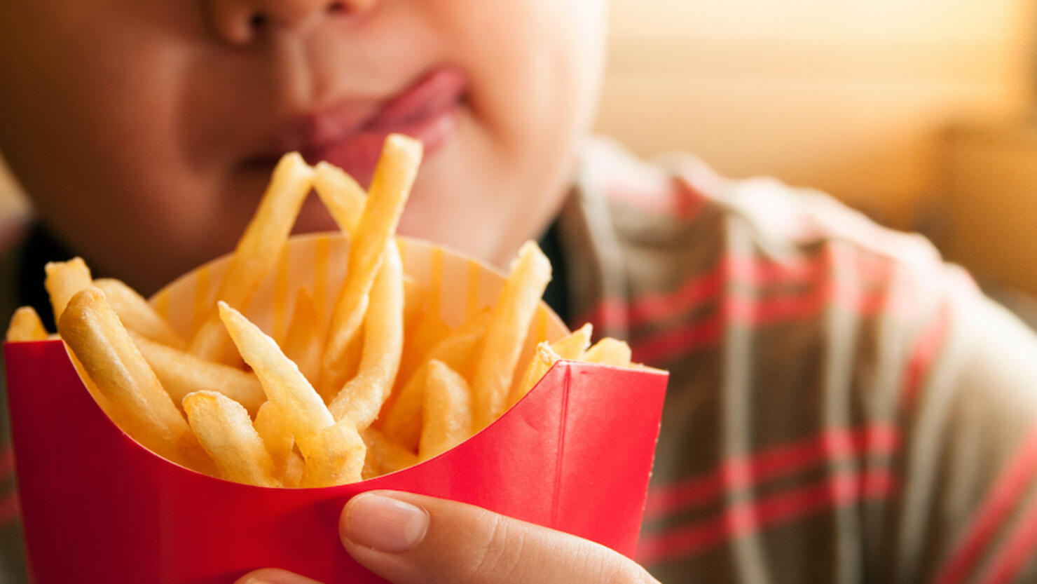 Cropped Image Of Tempted Boy Holding French Fries Packet