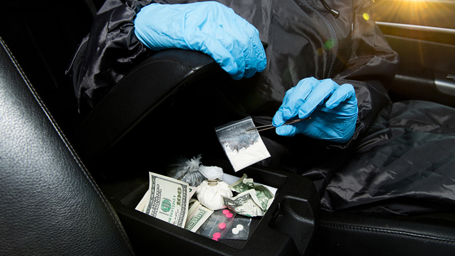 gloved policeman pulls cocaine from the armrest with tweezers