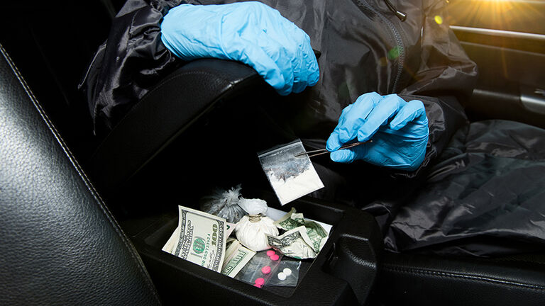 gloved policeman pulls cocaine from the armrest with tweezers