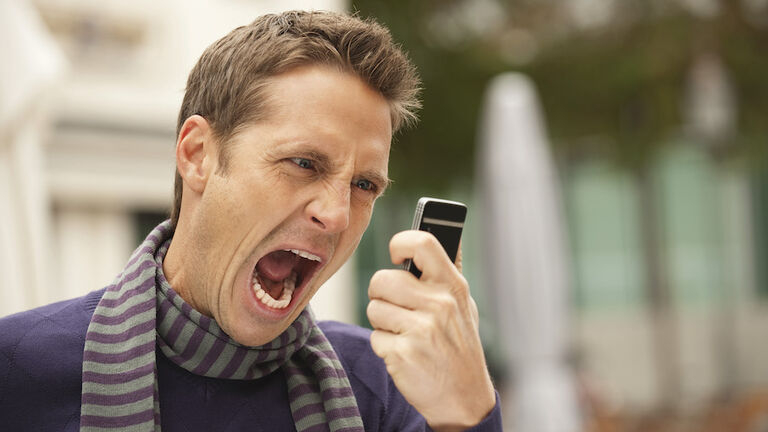 Germany, Bavaria, Munich, Man holding mobile phone, screaming, portrait