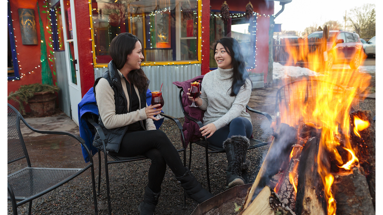 Women drinking cocktails outdoors at storefront campfire